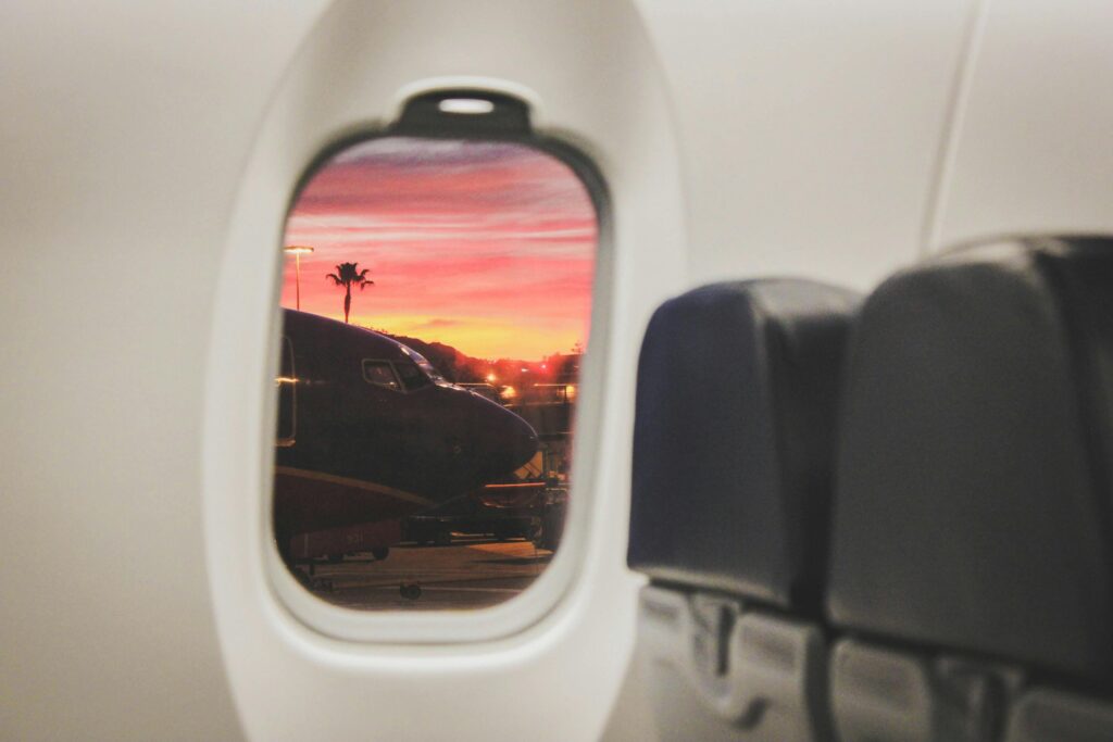 White commercial plane window looking out to a sunset
